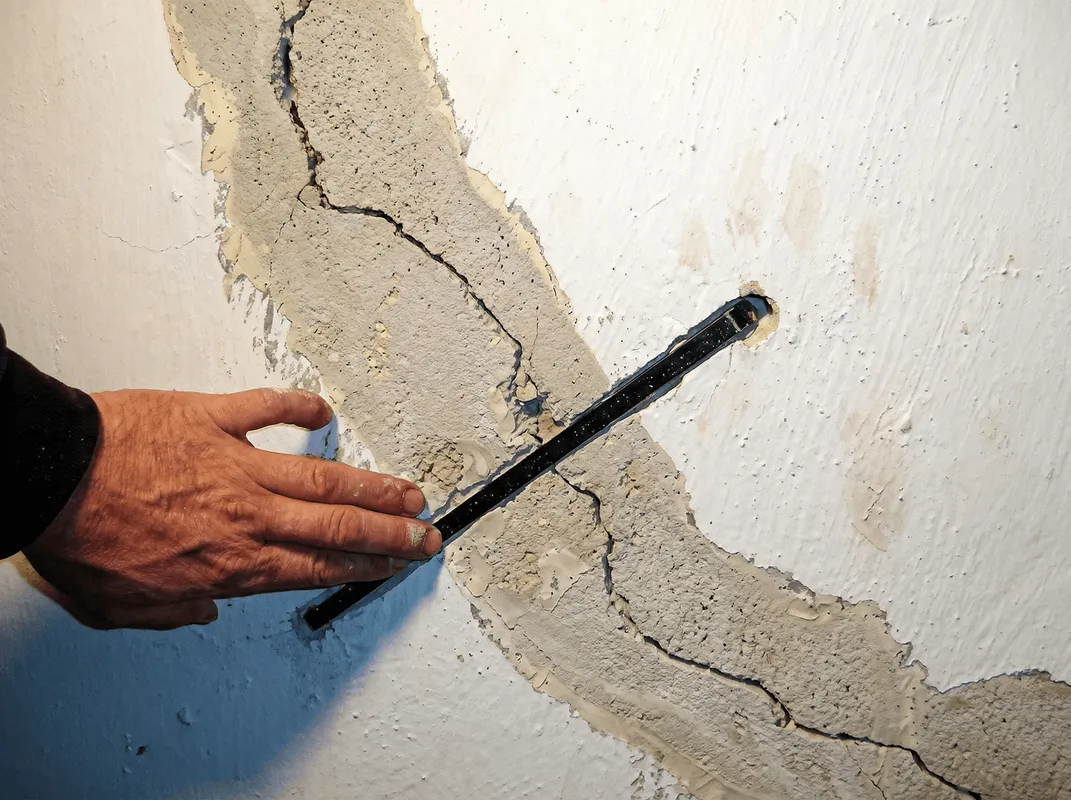 A wall with a large crack is being inspected by a professional in Providence, RI